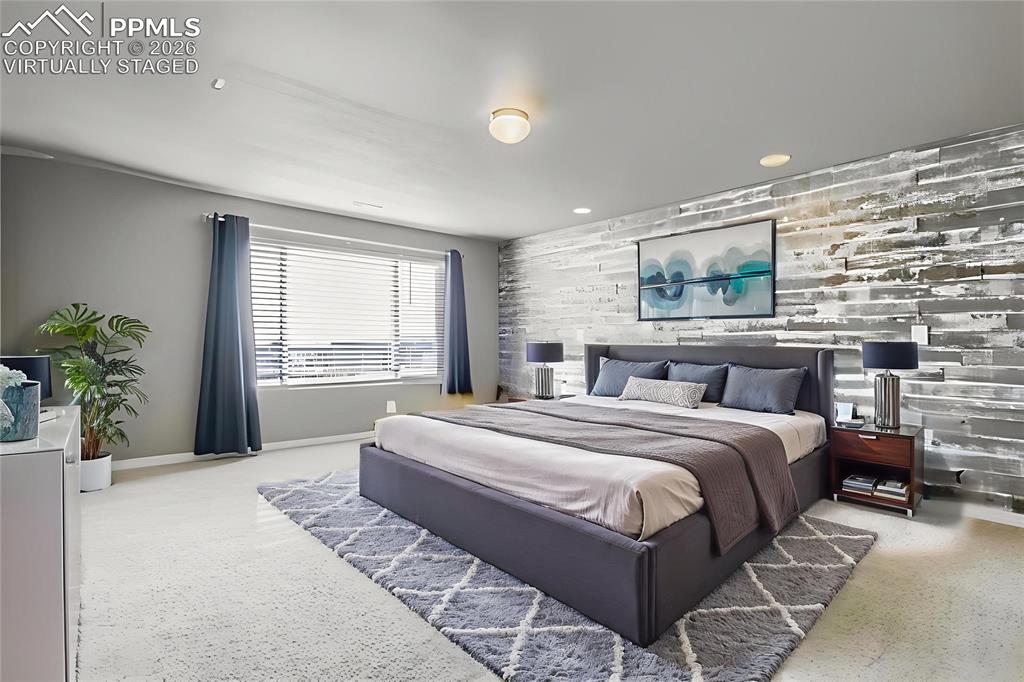 Virtually staged primary bedroom featuring an accent wall, wood walls, and recessed lighting