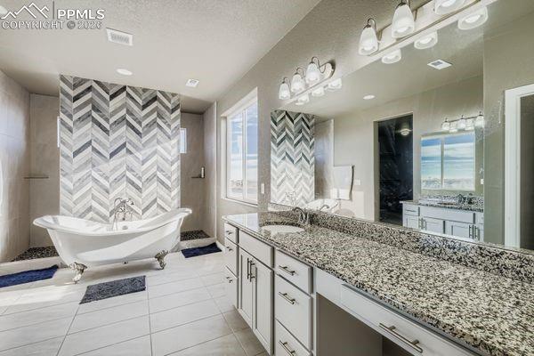 Full bathroom with vanity, a soaking tub, and light tile patterned floors
