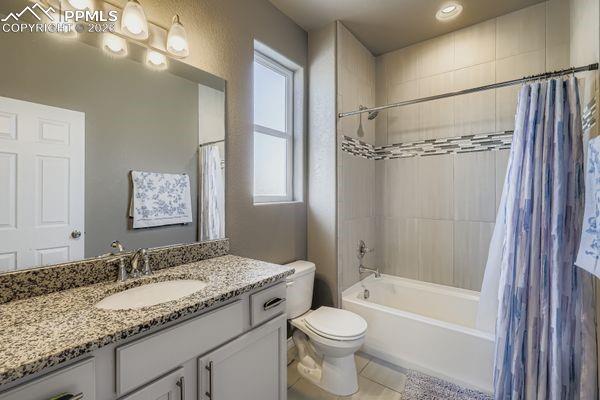 Full bathroom featuring shower / bath combo with shower curtain, vanity, and light tile patterned floors