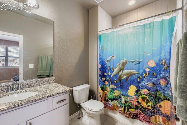 Full bath featuring vanity, a textured wall, shower / tub combo, and tile patterned floors