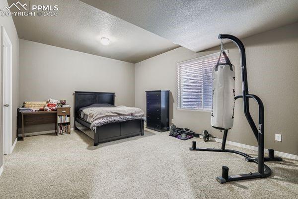 Carpeted bedroom featuring a textured ceiling and baseboards