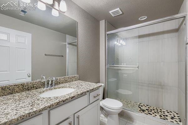 Full bath featuring a shower stall, vanity, a textured wall, a textured ceiling, and tile patterned floors