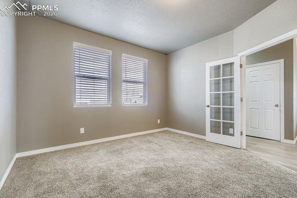 Main level office featuring light colored carpet and a textured ceiling