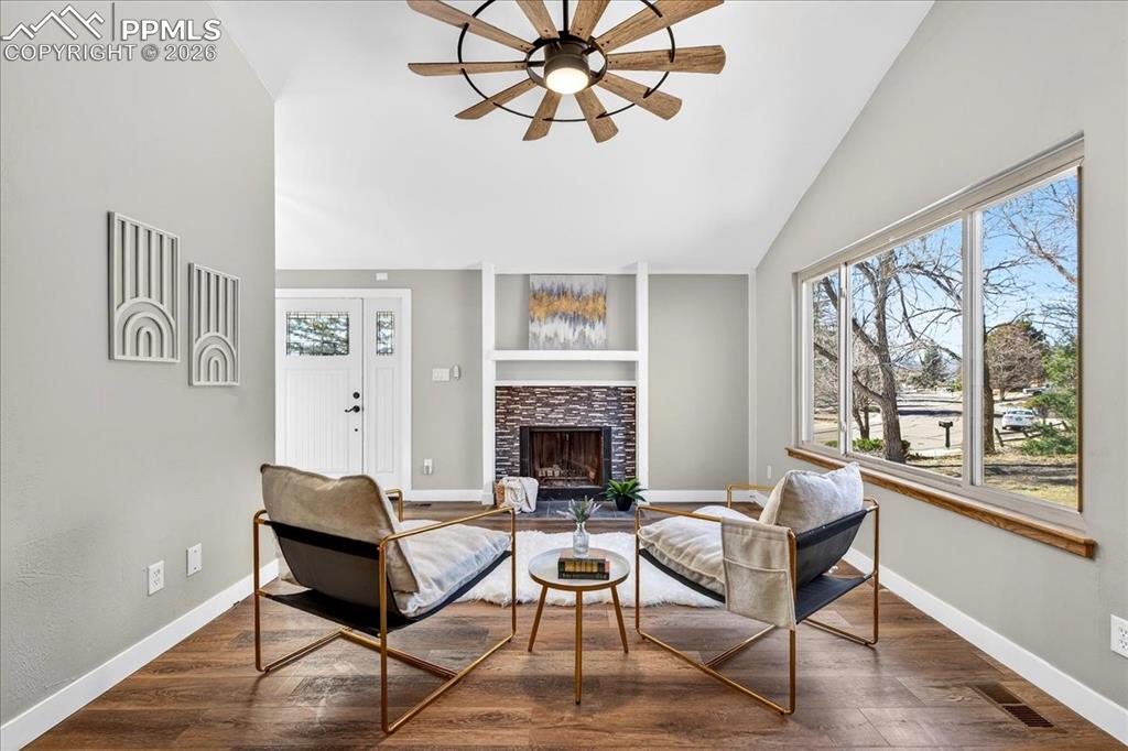 Living area featuring wood finished floors, a tile fireplace, ceiling fan, and vaulted ceiling