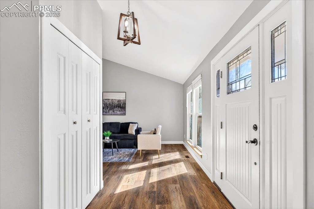 Foyer entrance featuring lofted ceiling, dark wood finished floors, and hanging lights