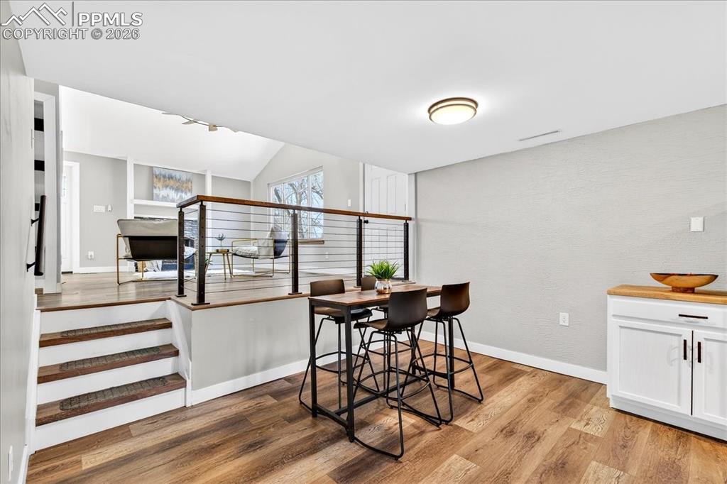 Dining room with light wood-type flooring and vaulted ceiling