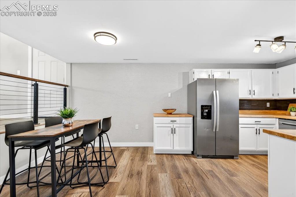Kitchen featuring stainless steel appliances, white cabinetry, light wood-style floors, and wooden counters