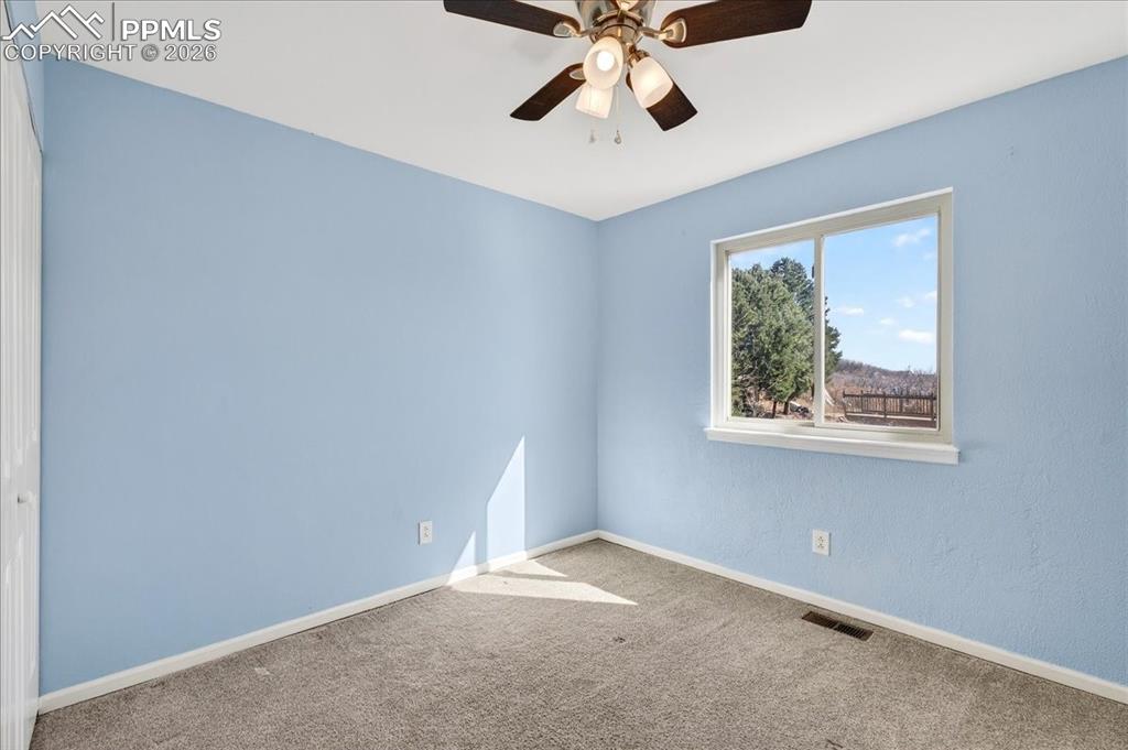 Carpeted empty room featuring baseboards and ceiling fan