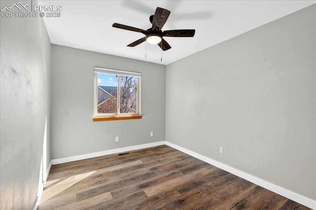 Empty room with dark wood-style floors and a ceiling fan