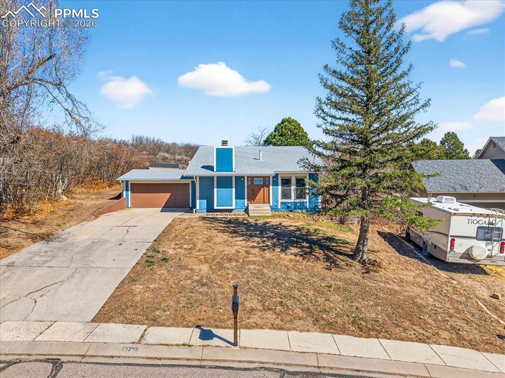 View of front facade featuring a chimney, driveway, and a garage