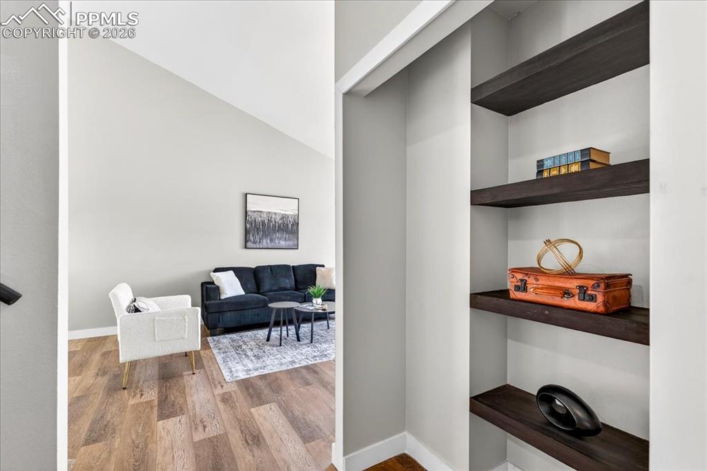 Hallway with light wood-type flooring and vaulted ceiling