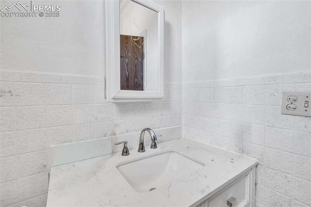 Bathroom with vanity and tile walls