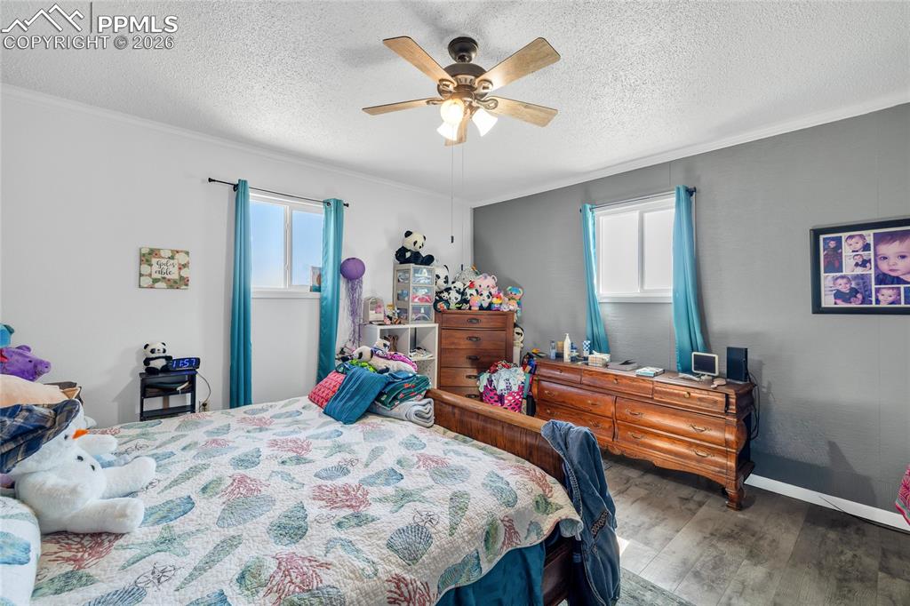 Bedroom featuring dark wood-style floors, ceiling fan, a textured ceiling, and ornamental molding