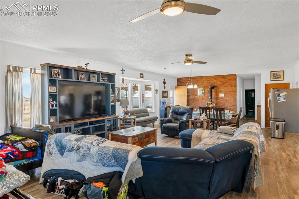 Living room featuring wood finished floors, a textured ceiling, and ceiling fan