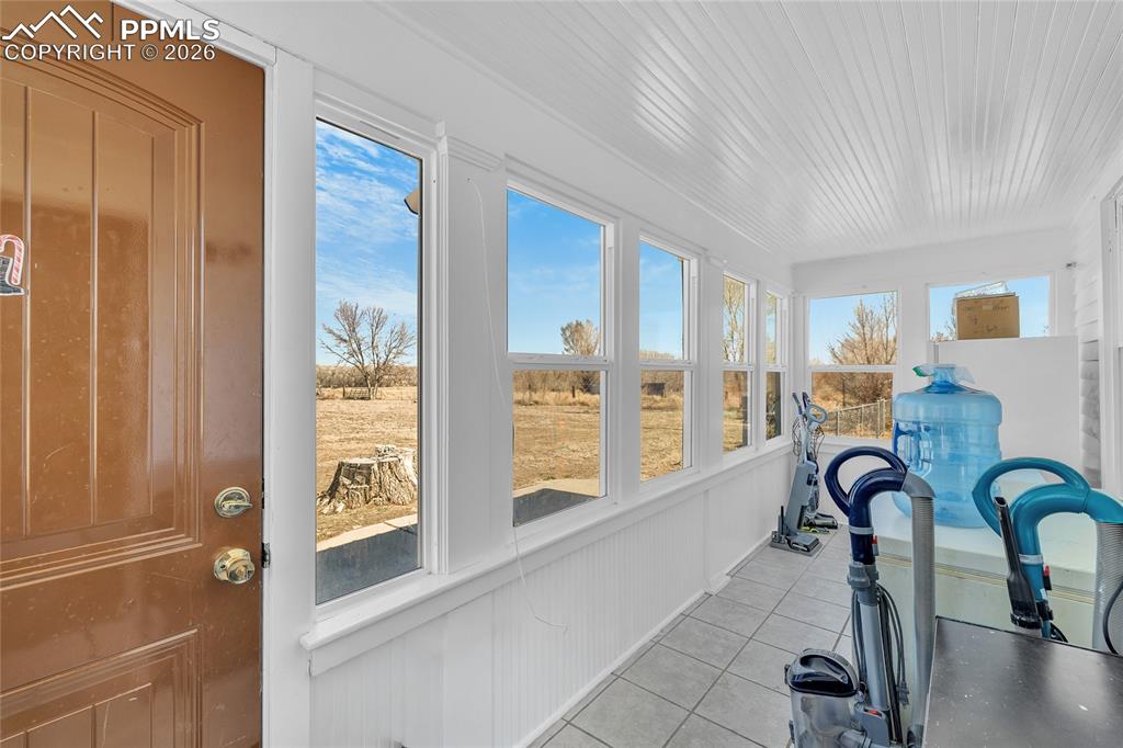Sunroom / solarium with tile patterned floors and wooden ceiling