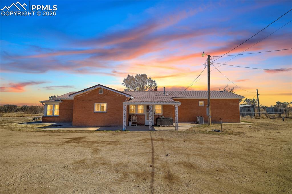Back of property at dusk with brick siding and a patio