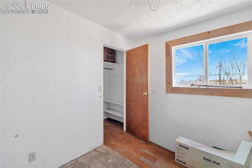 ADU Unfurnished bedroom featuring light wood finished floors, a textured ceiling, and heating unit
