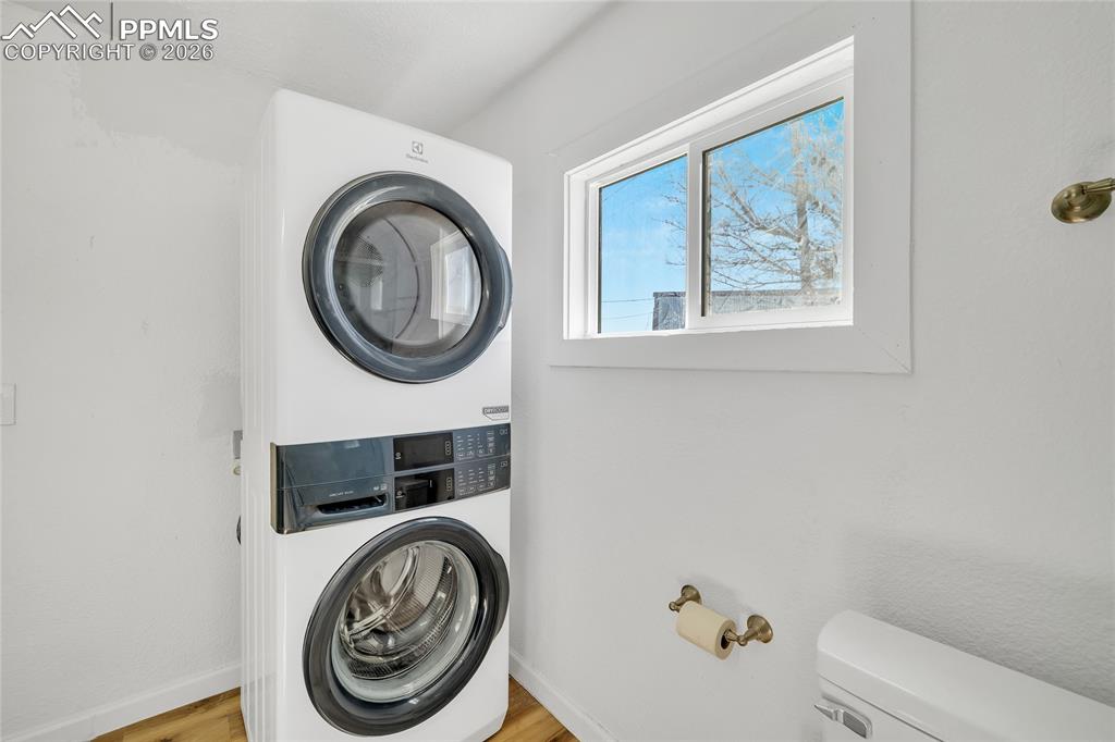 ADU Laundry area featuring stacked washer / dryer and light wood-style flooring