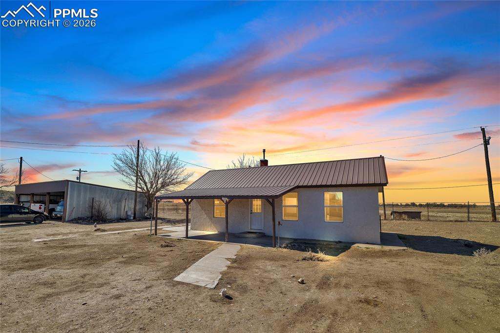 View of front of property with a metal roof, covered porch, and stucco siding