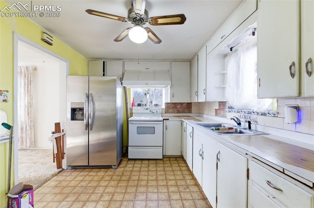Kitchen with light floors, stainless steel fridge with ice dispenser, light countertops, white electric range, and white cabinetry