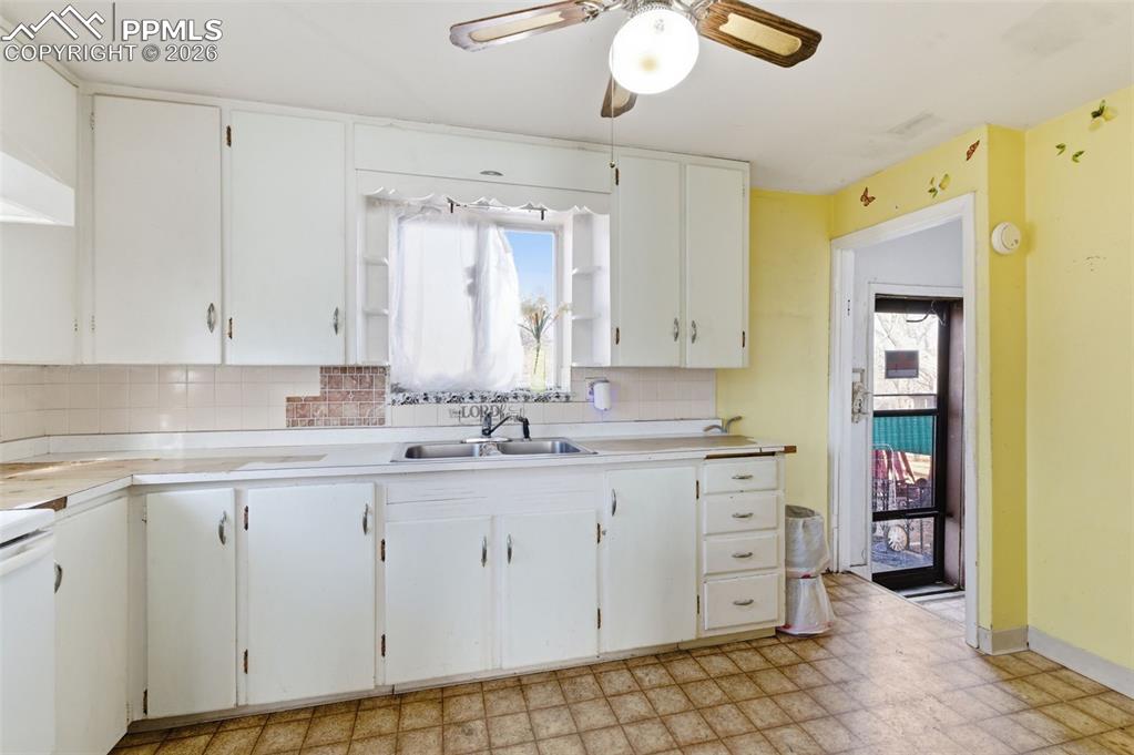 Kitchen featuring light flooring, white cabinetry, light countertops, and a ceiling fan