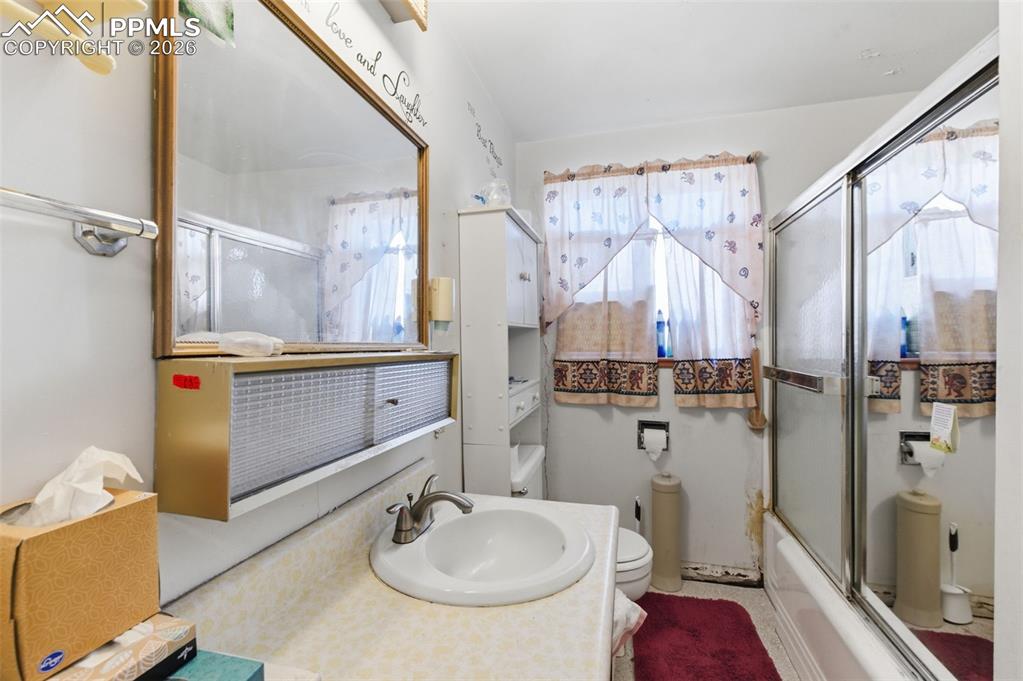 Full bath featuring vanity and bath / shower combo with glass door