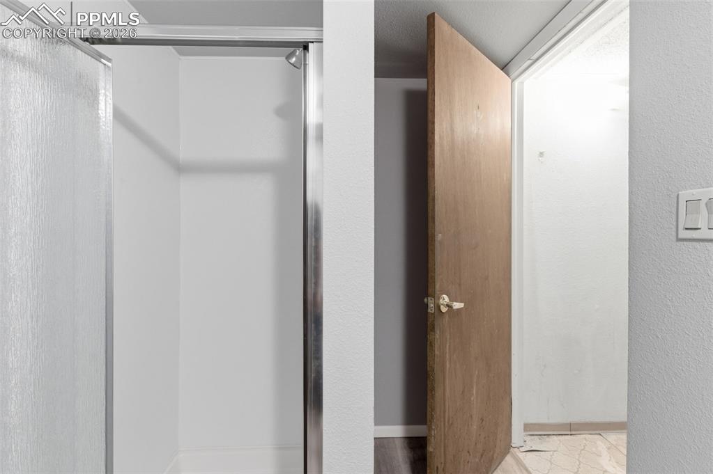 Bathroom with a stall shower and a textured wall