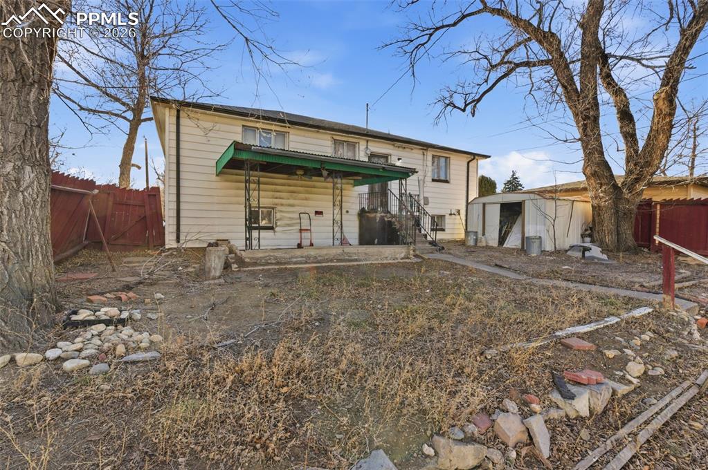 Rear view of house with a fenced backyard, a storage unit, and a gate