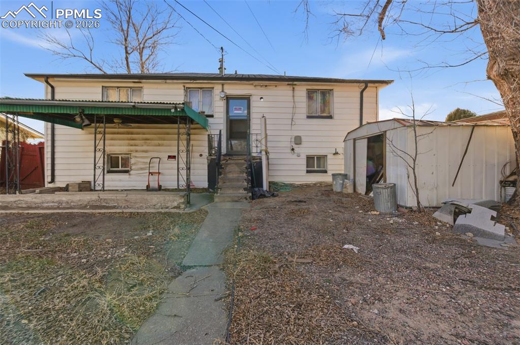 Back of house featuring a storage unit and a porch