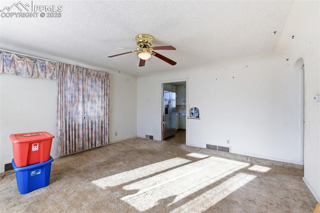 Empty room with a textured ceiling and a ceiling fan