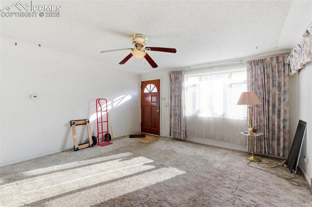 Carpeted entrance foyer with a textured ceiling and ceiling fan