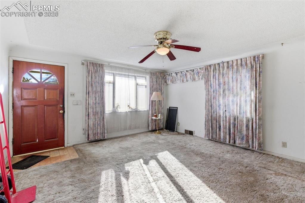 Entrance foyer with carpet floors, ceiling fan, and a textured ceiling