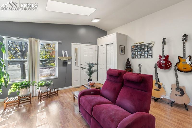 Living area with vaulted ceiling, a skylight, and light wood finished floors