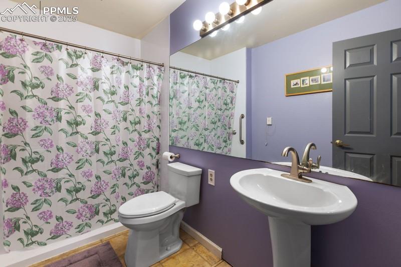 Bathroom with curtained shower and light tile patterned floors