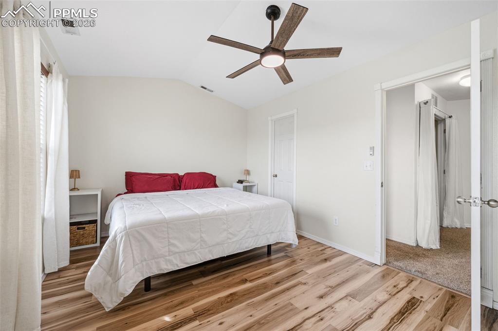 Bedroom with lofted ceiling, light wood-style floors, and ceiling fan