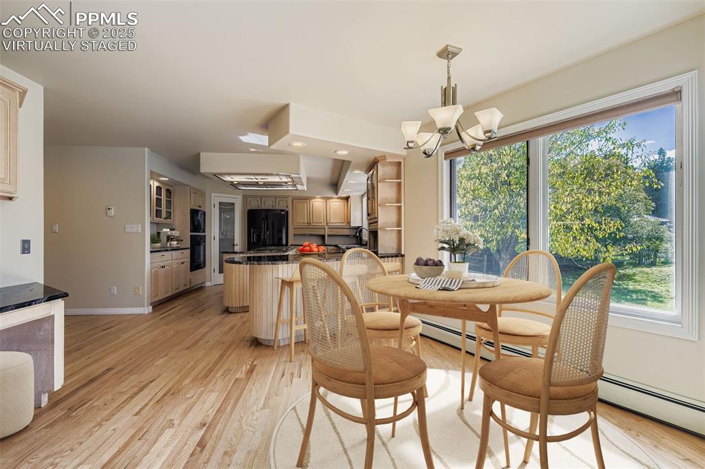 Virtually Staged! Dining space with light wood finished floors, a chandelier, and a baseboard heating unit, refinished hardwood floors (main floor)