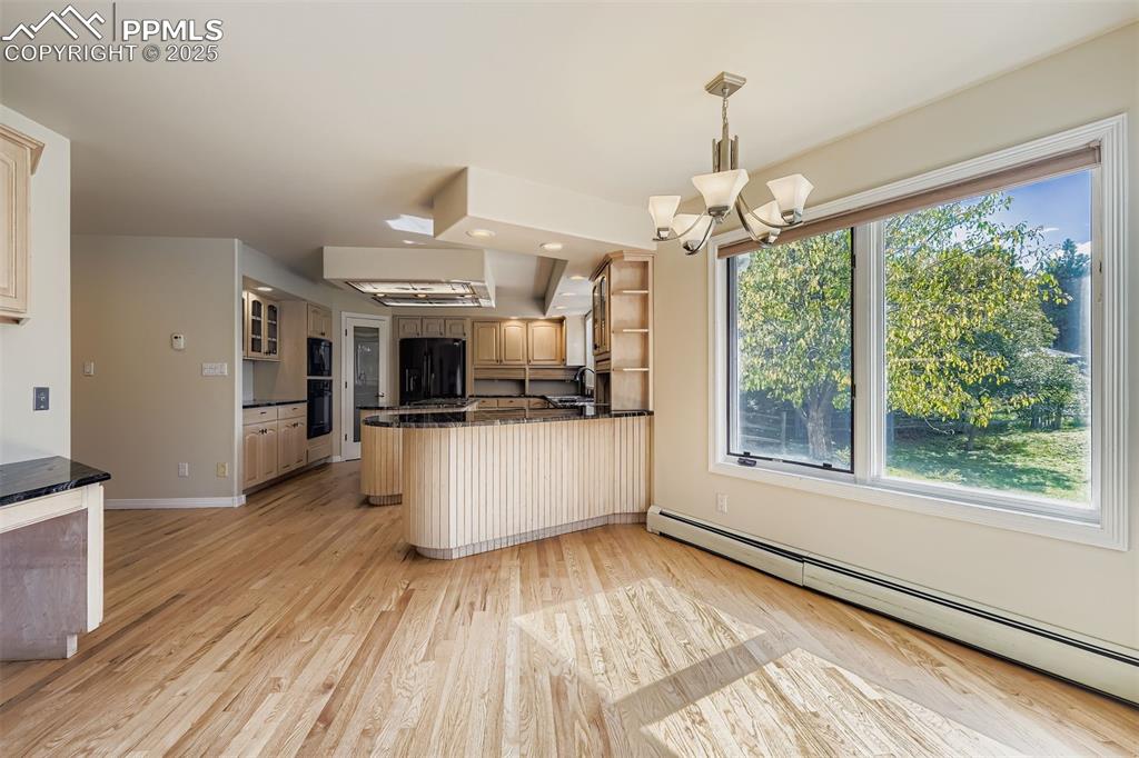 Dining space with light wood finished floors, a chandelier, and a baseboard heating unit, refinished hardwood floors (main floor)