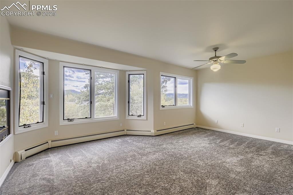 Primary Bedroom featuring carpet floors, baseboard heating, gas fireplace and a ceiling fan (upper level)