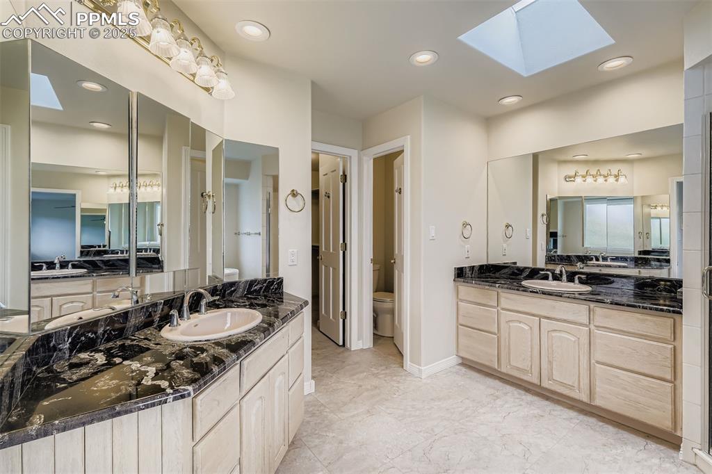 Bathroom with a skylight, two vanities, recessed lighting, and light, vinyl flooring, new granite counter tops
