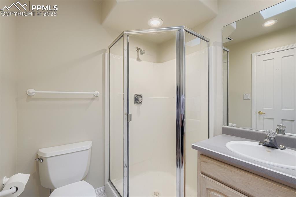 Ensuite 3/4 bathroom with vanity, freestanding shower, recessed lighting, and a skylight