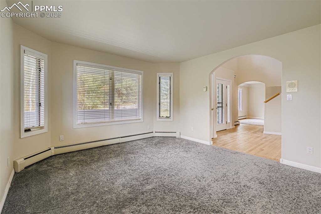 Office featuring arched walkways, light carpet, and a baseboard heating unit (main floor)