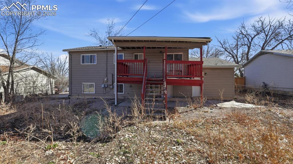 Rear view of home with covered deck and concrete patio.