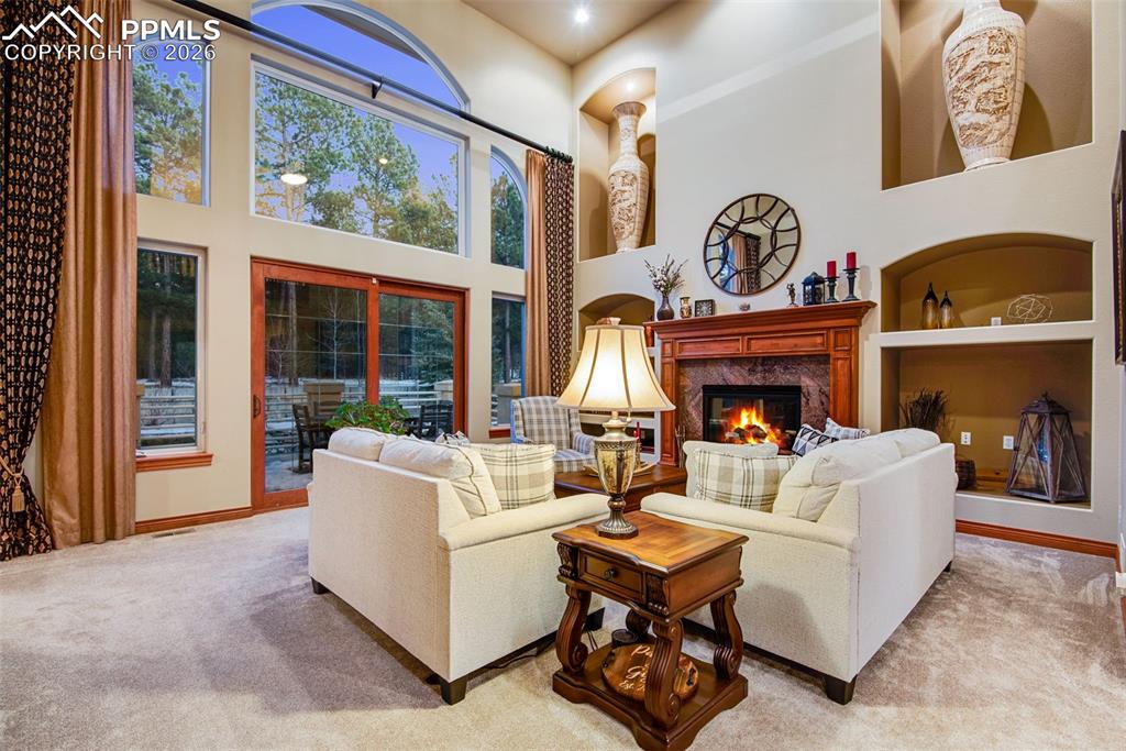 Living room with gas fireplace, custom built-ins and floor to ceiling windows overlooking the trees