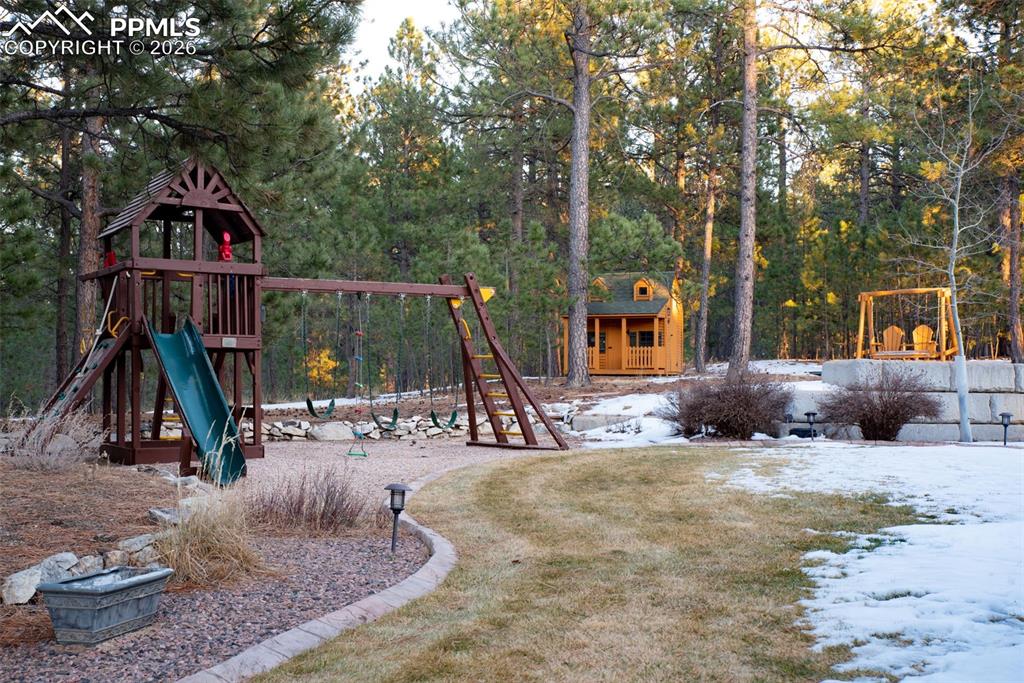 Backyard includes a play structure, play house, in-ground trampoline, and outdoor swing