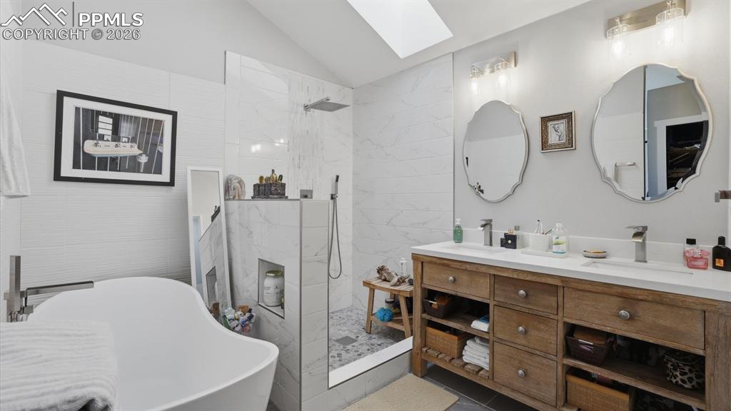 Luxurious 5pc Primary Bathroom with dual sink vanity, round mirrors, walk in shower with rain shower head, and soaking tub.