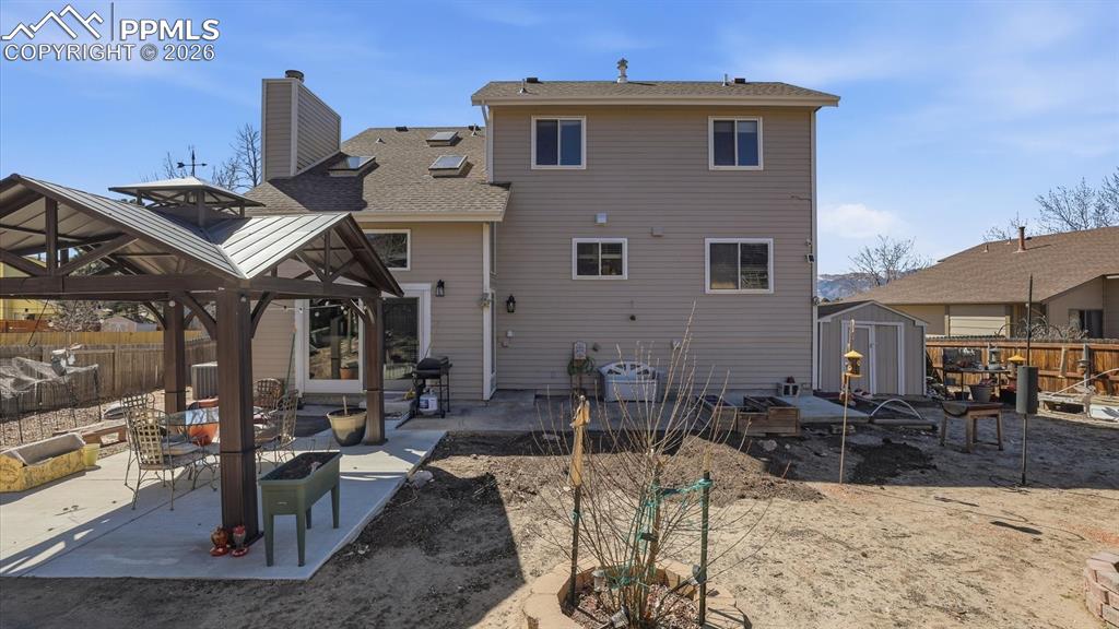 Rear view of home, patio with gazebo, and storage shed for tools and equipment.