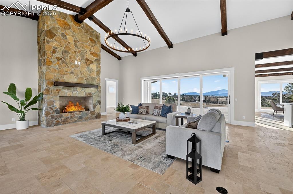 Living room featuring a mountain view, stone tile floors, a stone fireplace, suspended lighting, and lofted ceiling