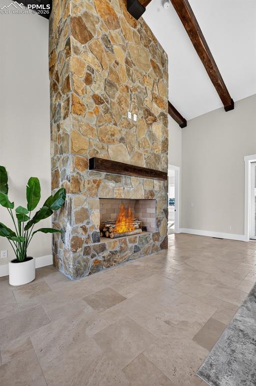 Unfurnished living room featuring a stone fireplace, stone tile flooring, and vaulted ceiling