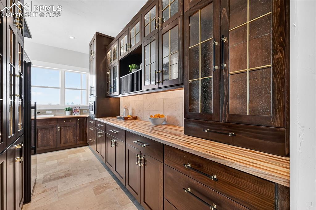 Bar with dark wood finish cabinets, backsplash, wood counters, glass insert cabinets, and recessed lighting