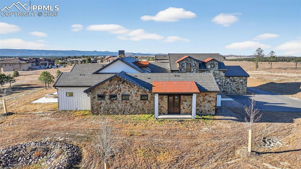 View of front facade with stone siding, roof mounted solar panels, and covered porch